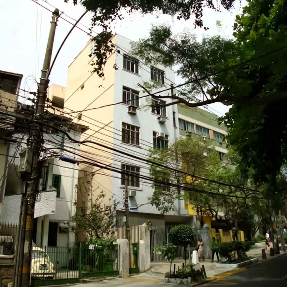 Fachada do Condomínio Edifício Marmax em Laranjeiras, prédio multifamiliar de vários andares com janelas e grades, visto a partir da rua com fiação elétrica aparente.
