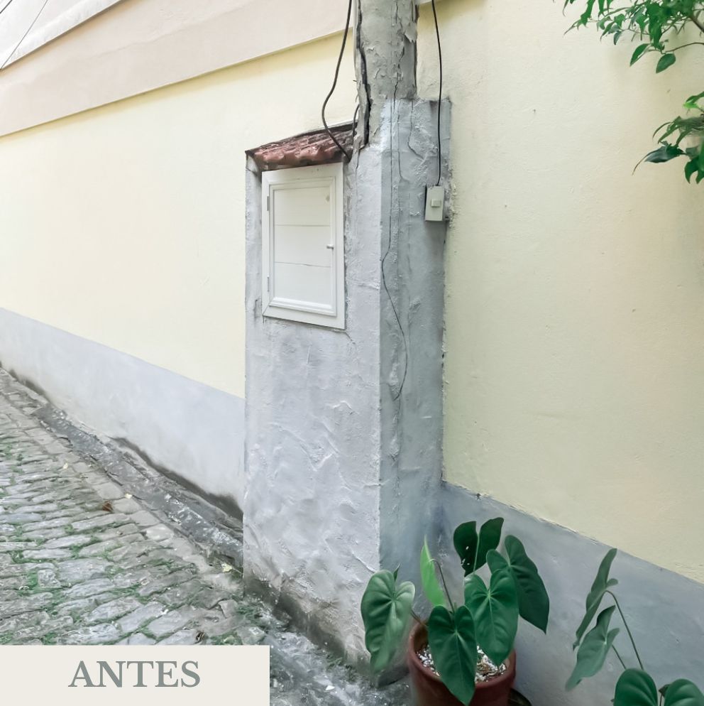Painel de iluminação externo antes da reforma, com fiação exposta, caixa elétrica desgastada sem proteção e parede com reboco irregular.