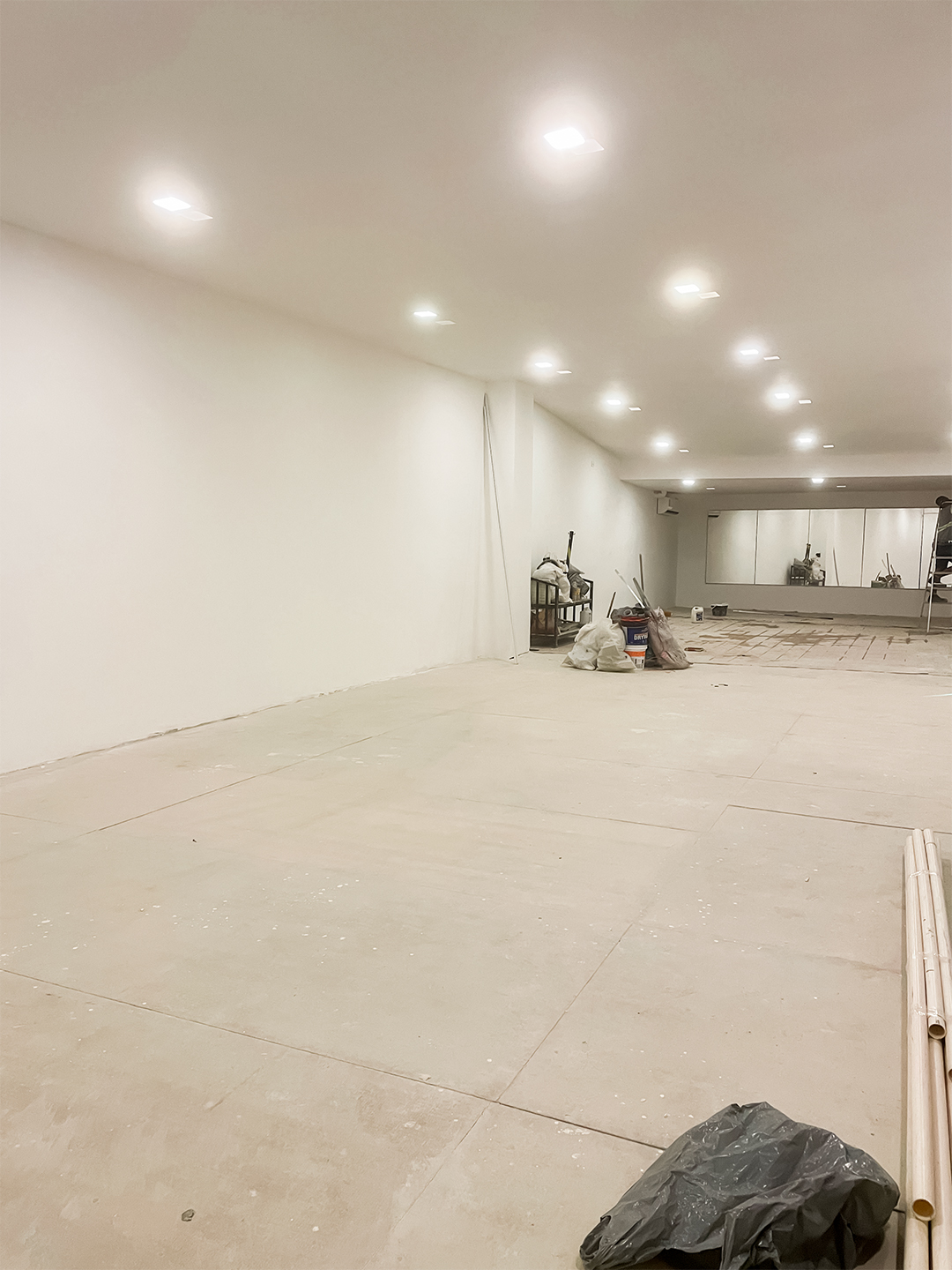 Salão do mezanino reformado com piso claro, paredes brancas, iluminação embutida no teto e amplo espaço interno pronto para uso.